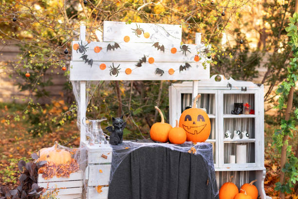 Halloween orange pumpkin head jack lantern with statuette cat bat. Festive composition on table decorated with pumpkins, bats, spiders, cobwebs and witch magic attributes. Halloween design decor home linterna de jack de cabeza de calabaza naranja de halloween con murciélago de gato estatuilla. composición festiva sobre mesa decorada con calabazas, murciélagos, arañas, telarañas y atributos mágicos de brujas. decoración de diseño de halloween pa