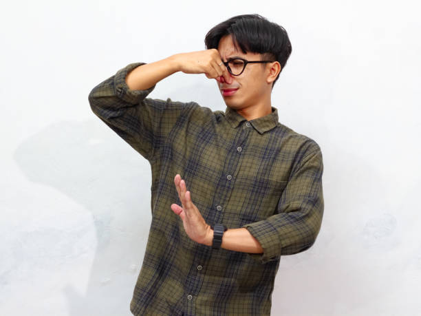 istock Young handsome Asian man covering his nose with his hand while showing a stop gesture with his hand, isolated on a white background. 2171705722