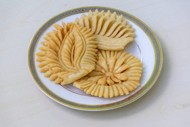 istock Crispy Nakshi Pitha on a white plate on a light wooden surface. It is a traditional Bengali (Bangladesh) food, also known as Pakkon Pitha. This type of pitha is made from rice flour. 2171712865