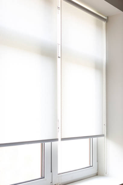 istock White roller blinds covering windows in a sunlit interior during the daytime 2171714042