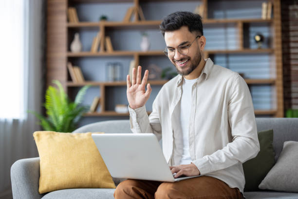 istock Smiling man video chatting on laptop from comfy couch in modern home 2171721780