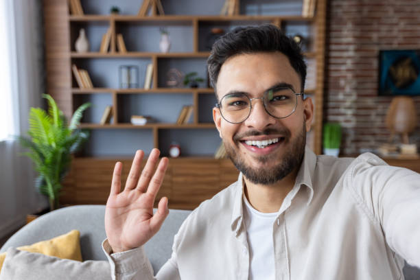 istock Young man waving and smiling during video call using phone at home 2171721789