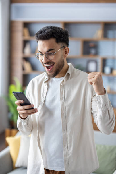 istock Excited man celebrating success while looking at smartphone at home 2171721797