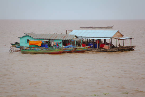 Floating village homes in Cambodia showcase life along the water during the day Colorful houses on stilts rise above the water in a floating village in Cambodia, reflecting vibrant local life amidst serene surroundings during daylight hours. small houseboats stock pictures, royalty-free photos & images