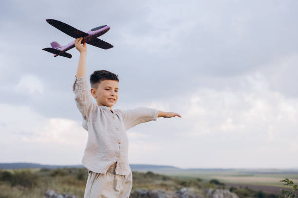istock Joyful Boy Playing with Toy Airplane in Open Field on a Cloudy Day 2171727517