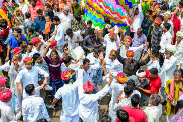 Beawar, Rajasthan, India, September 13, 2024: Thousands of Hindu devotees gather to offer prayers at a temple during Teja Dashami festival celebrations in Beawar. They offer colorful religious flags & garland to folk deity Teja and dance on dhol beats. Veer Teja is considered one of the major eleven incarnations of Lord Shiva and worshipped as a deity in rural Rajasthan. He was born around 1074 in Khadnal village of Rajasthan and died in 1103. Legend has it that Teja died because of snake bite. He allowed a snake to bite his tongue, that being only unwounded area of his body. In return, snake promised that no person or animal would die from a snakebite if they sought blessings of Teja.