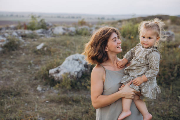 istock Mother Holding Daughter Outdoors in Scenic Nature Setting During Sunset 2171734848