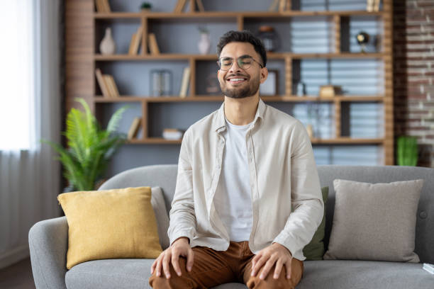 istock Young man relaxing at home with eyes closed, enjoying peaceful moment on comfortable sofa with colorful cushions 2171735258