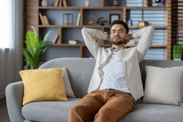 istock Young man relaxing on comfortable sofa at home, enjoying peaceful moment with hands behind head 2171735286