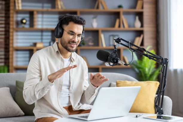 istock Confident young man recording podcast at home while using laptop and microphone, engaging with audience through live streaming and headphones 2171735687