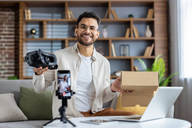 istock Smiling man creating unboxing video with smartphone as he showcases virtual reality headset in home setting 2171736339