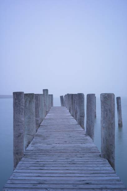 istock Serene wooden pier extending into a misty lake. 2171740333