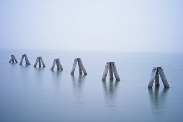 istock Wooden structures in calm water under foggy sky 2171740336