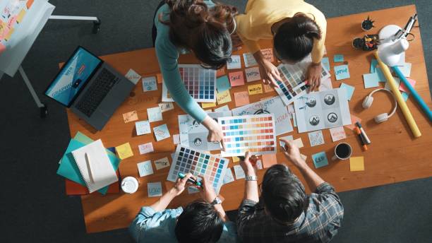 istock Top view of skilled designer holding logo while discussing with team. Symposium. 2171748586