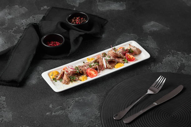 istock Elegant Sliced Beef Roast with Cherry Tomatoes on a Textured Slate Background 2171756657