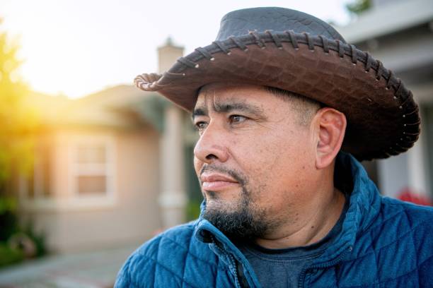 Serious pensive mature hispanic man looking away wearing a cowboy hat