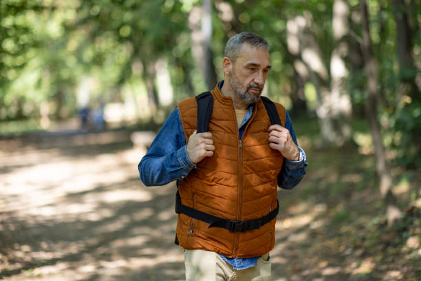 Solitary man meandering through sunlit woodland path.