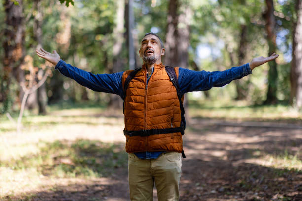 Joyful man embraces nature with uplifted hands view.