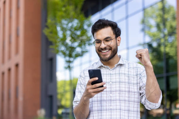 istock Happy man celebrating success while looking at smartphone outdoors 2171768802