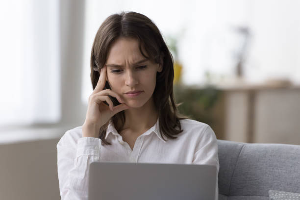 istock Frowning woman sit on sofa look at laptop screen 2171770216