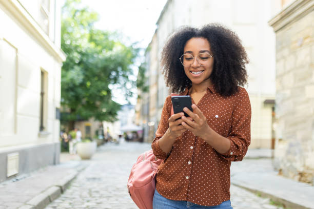istock Smiling woman using smartphone outdoors on a sunny day 2171775181