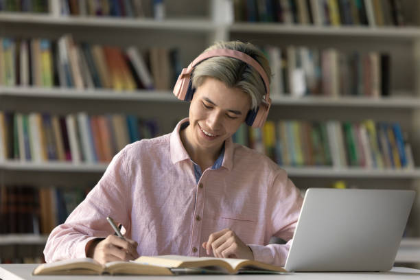istock Focused student guy in pink wireless headphones studying in library 2171780473