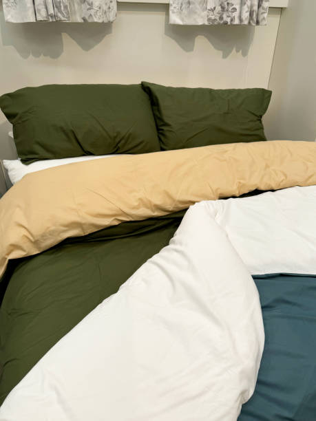 istock Image of double bed with olive green pillows, folded back duvet, cream top sheet, white lower bedsheet, elevated view, focus on foreground, home furnishings concept 2171780712