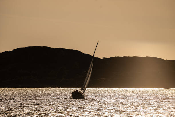 Sailboat journeying into the sun on a windy day.