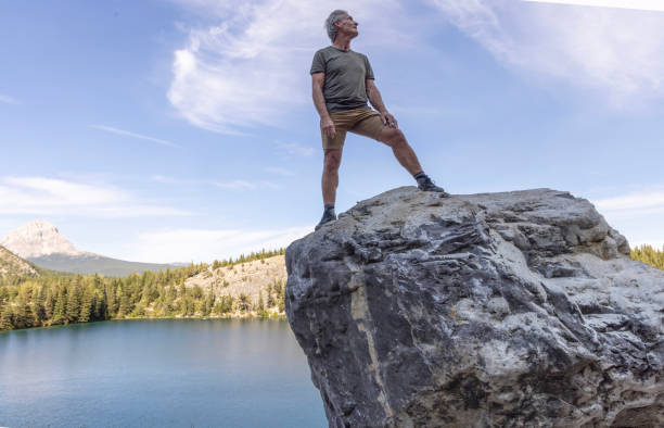 Mature man on boulder above lake, Crowsnest Pass, Canadian Rockies