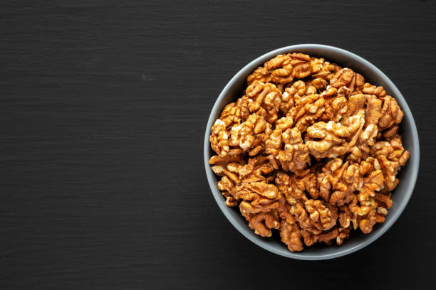 istock Raw Organic Walnuts in a Bowl on a black background, top view. Flat lay, overhead, from above. Copy space. 2171879646