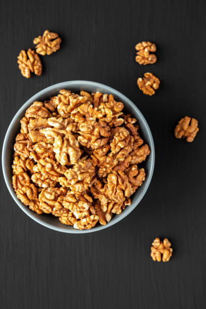 istock Raw Organic Walnuts in a Bowl on a black background, top view. Flat lay, overhead, from above. 2171879688