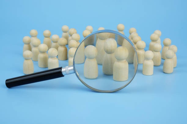 istock Many wooden figures under magnifying glass on blue background. 2171887944