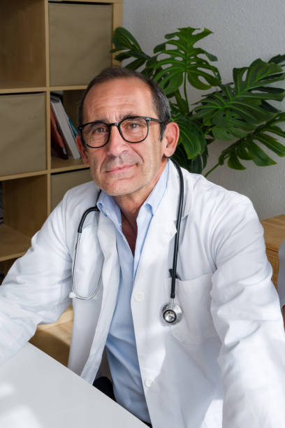 istock Senior doctor sitting at desk with stethoscope in office 2171893481