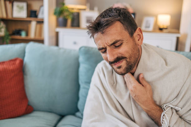 istock A sick mid adult man is sitting on a sofa. 2171895385
