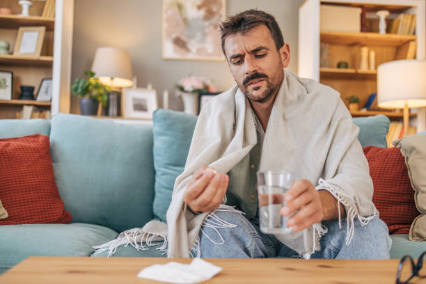istock A sick mid adult man is sitting on a sofa. 2171895462