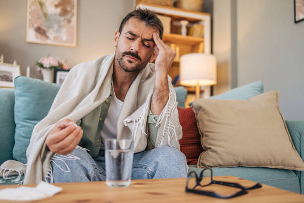 istock A sick mid adult man is sitting on a sofa. 2171895672