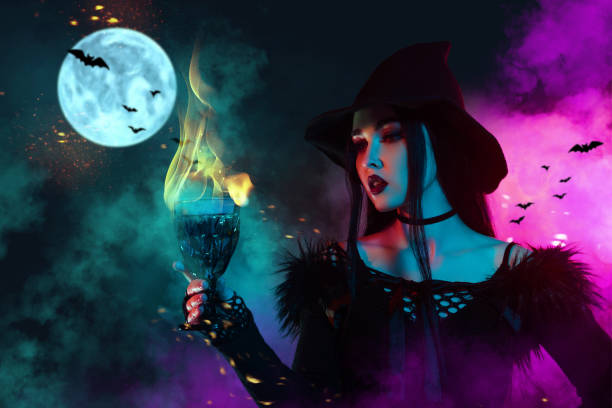 A young witch with jack o'lantern in a night misty forest. Smiling attractive woman with a carved pumpkin and smoke. Halloween party, trick or treat concept. Magic, witchcraft, sorcery. Banner with copy space