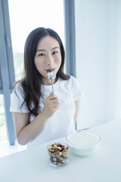 istock Asian woman eating yogurt with nuts for breakfast 2171906243