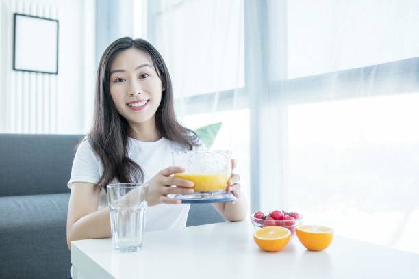 Asian woman making orange juice in the kitchen