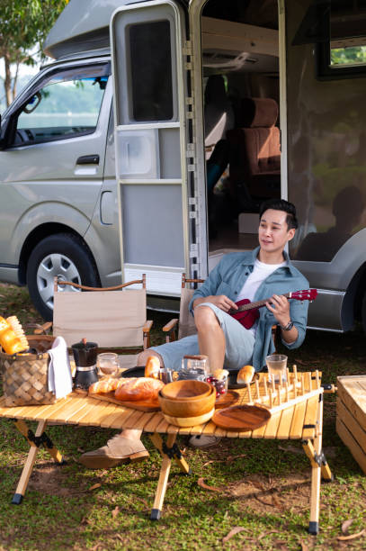 istock Cheerful Asian man joyful picnic adventure with camper van 2171915058