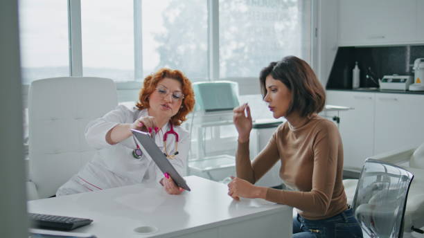 istock Focused physician holding tablet explaining data to patient at clinic closeup 2171923689