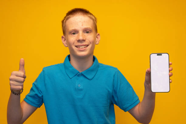 Indoor portrait of attractive young man isolated on gray background, holding smartphone, using voice control, feeling happy and surprised. Human emotions, facial expression concept.
