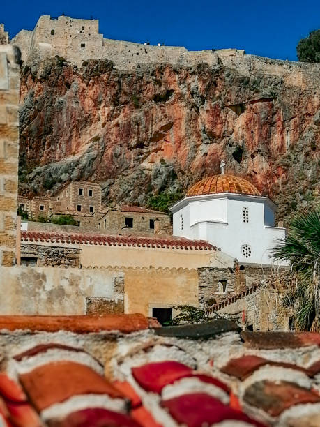 The Upper Town (Ano Poli), offers stunning panoramic views of the surrounding area. The ruins of old mansions and the impressive Church of Agia Sofia, one of the oldest Byzantine churches in Greece. Monemvasia, often referred to as the “Gibraltar of the East,” has a rich and varied history. Founded in 583 AD by inhabitants of the mainland seeking refuge from invasions, it quickly became an important commercial and maritime center. The town’s name comes from the Greek words “moni” (single) and “emvasis” (entrance), reflecting its unique access point.\n\nThroughout its history, Monemvasia was ruled by various powers, including the Byzantines, Franks, Venetians, and Ottomans. Each left its mark on the town, contributing to its diverse architectural and cultural heritage.