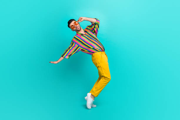 Full size photo of funny cheerful playful guy brunet haircut wear colorful shirt fingers hold glasses isolated on teal color background Full size photo of funny cheerful playful guy brunet haircut wear colorful shirt fingers hold glasses isolated on teal color background. gay man men sunglasses party stock pictures, royalty-free photos & images