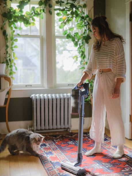 istock Woman vacuuming while cat plays with her 2171953973