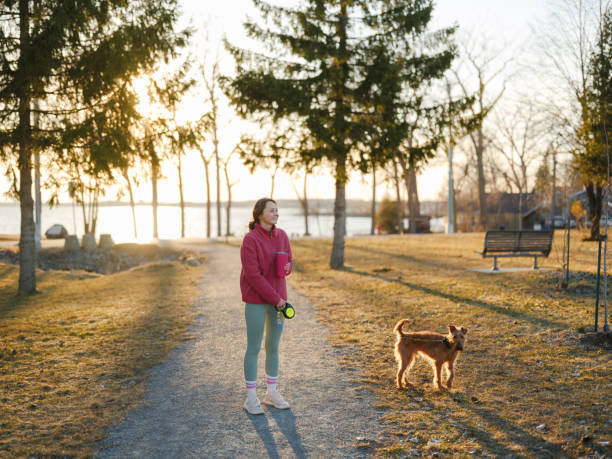 Woman on walk with dog in springtime at sunset