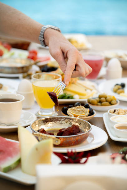 istock Man picking sausage from a breakfast plate at the poolside 2171955887