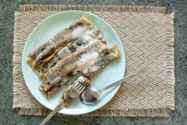 Moldy rotten toxic pancakes with jam on a plate with cutlery
