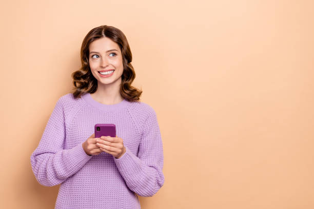 istock Portrait of cheerful girl wavy hairstyle dressed violet pullover chatting phone look empty space isolated on pastel color background 2171963532