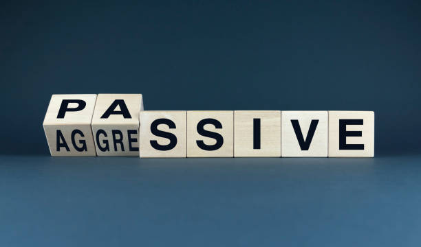 A conceptual image featuring wooden blocks spelling out PASSIVE AGGRESSIVE. The word is divided into two parts, symbolizing the internal conflict and duality of this complex behavioral pattern. Perfect for psychology, sociology, and self-help related projects